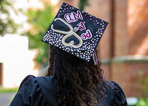 An SPU graduate with a decorated mortarboard reading 